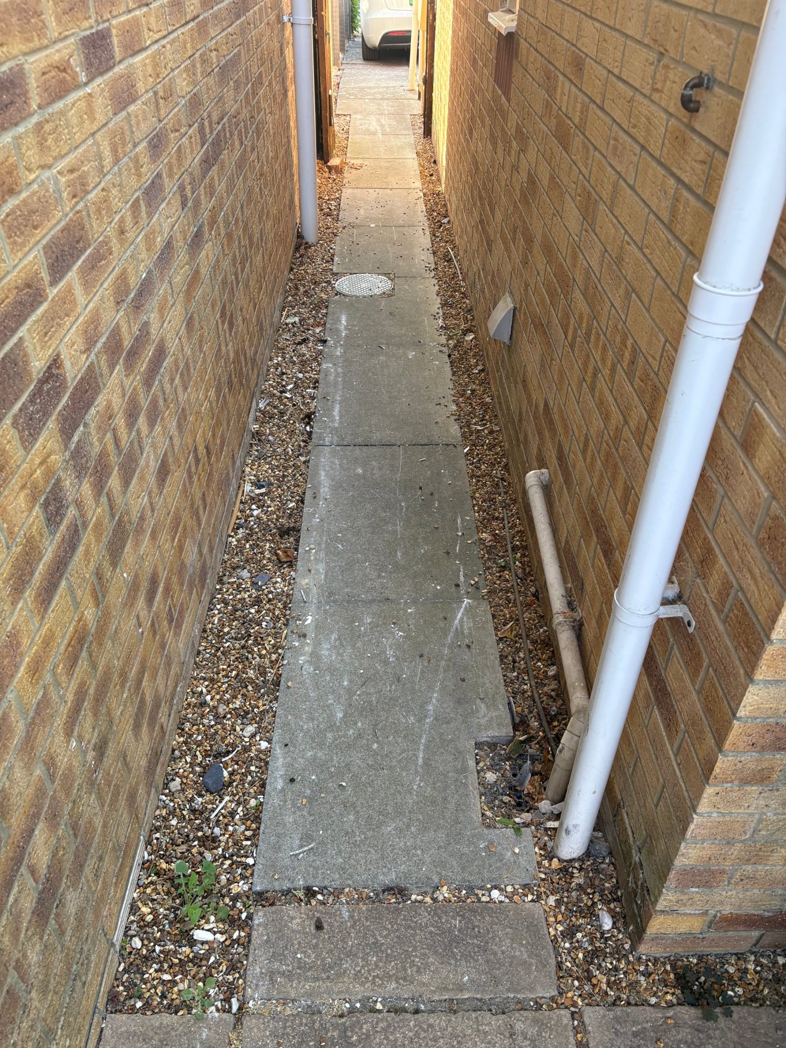 Before: the side return in worn concrete slabs with loose gravel either side.