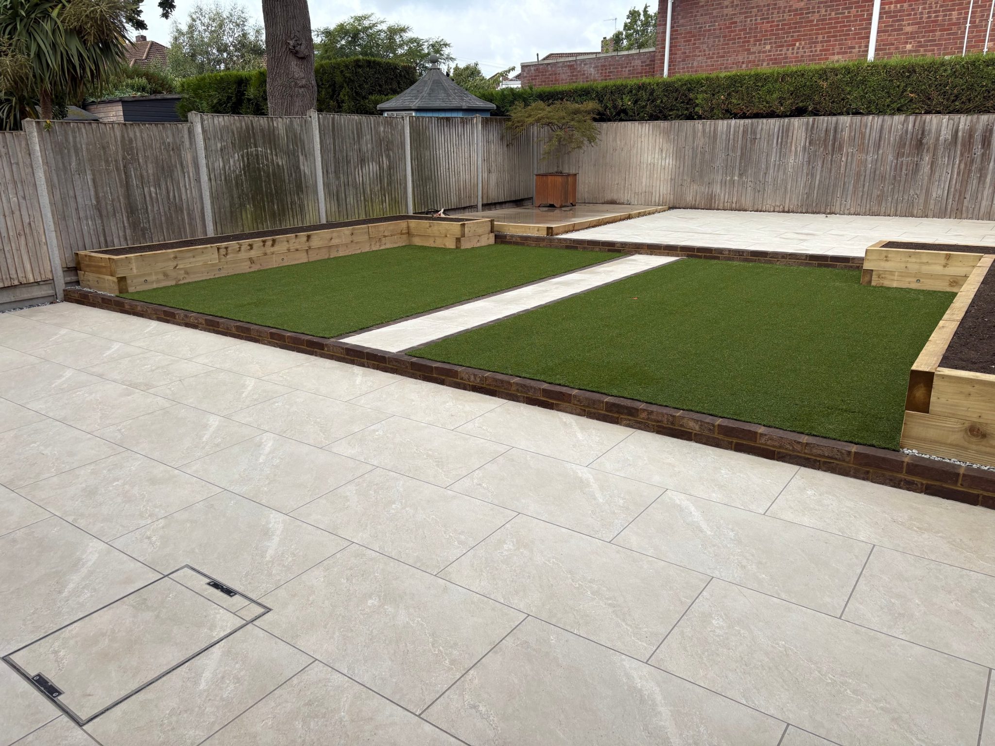 The terrace and middle tier from the side, showing the dark brick edge running the full width of the garden.