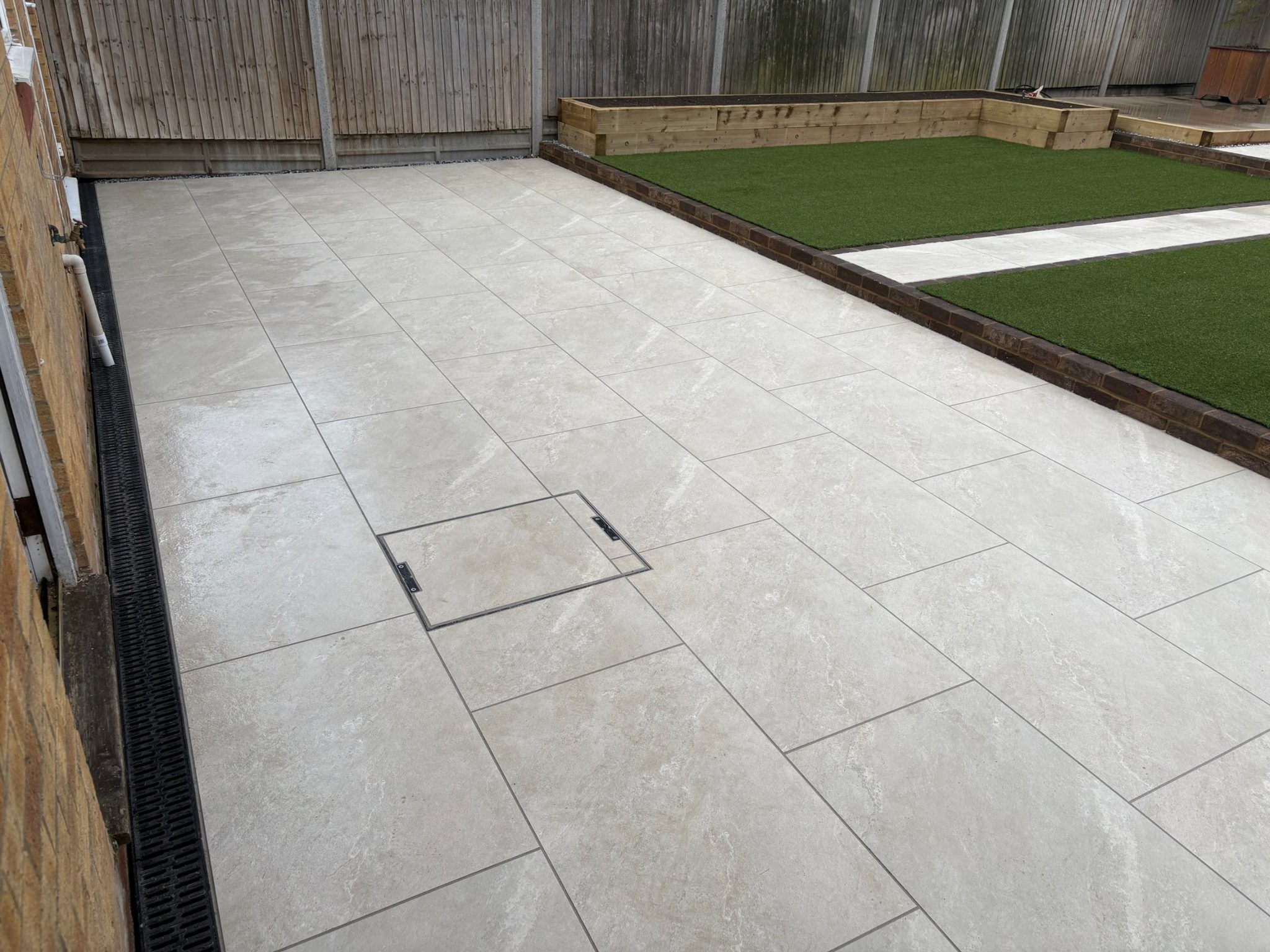 A recessed access cover in the terrace, filled with matching porcelain so it sits flush with the paving.