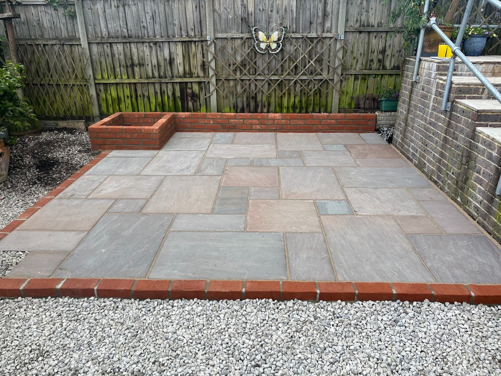 Bottom-of-garden sandstone patio with Ibstock red multi brick edging and planted retaining wall, Fareham