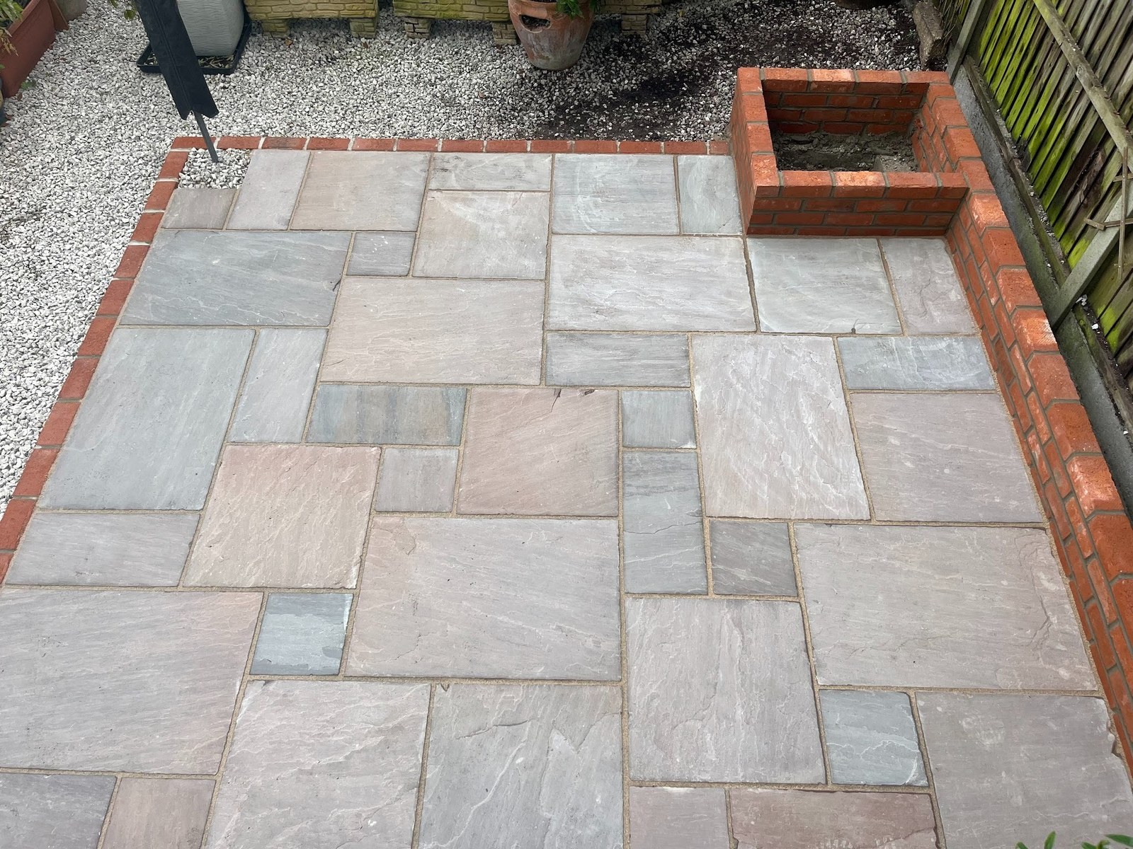 The completed patio in dry conditions &mdash; mixed-size Raj sandstone in random course, Ibstock red multi brick edging.