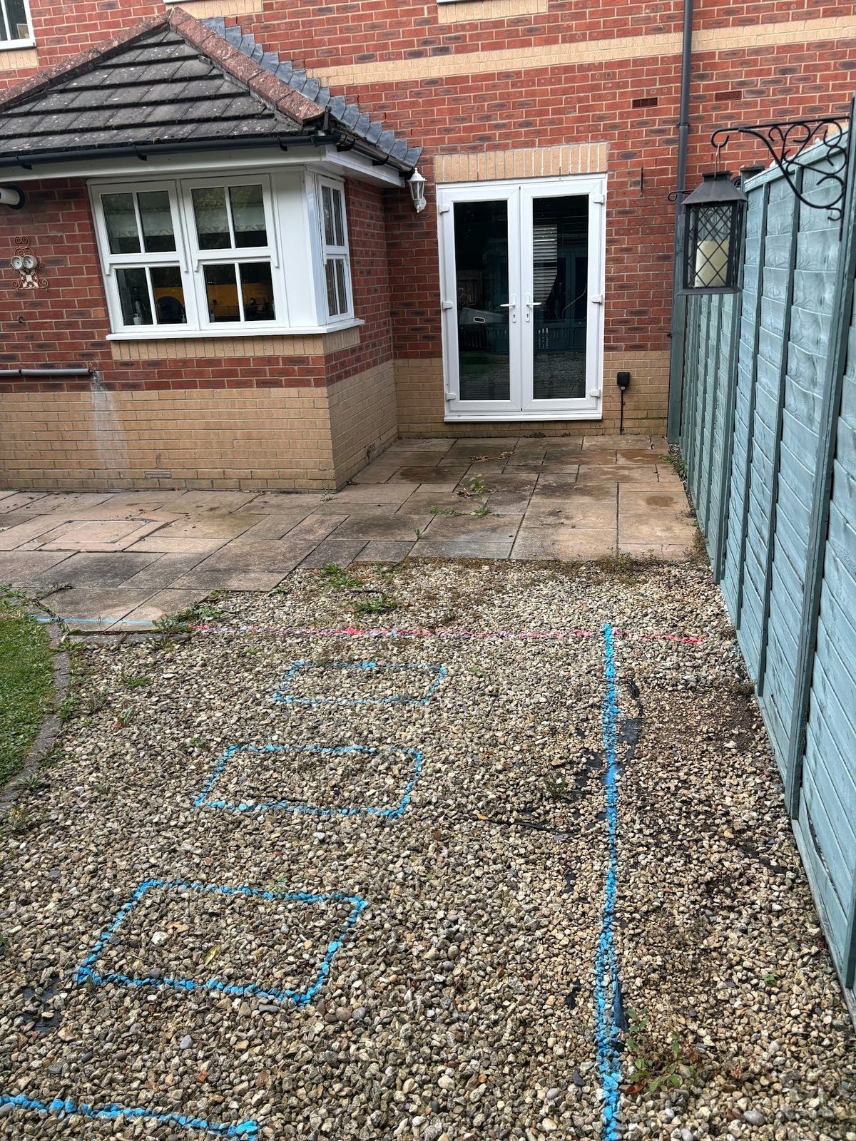 Before: the rear garden stripped back to gravel and old carpet underlay, marked out ready for the new patio.