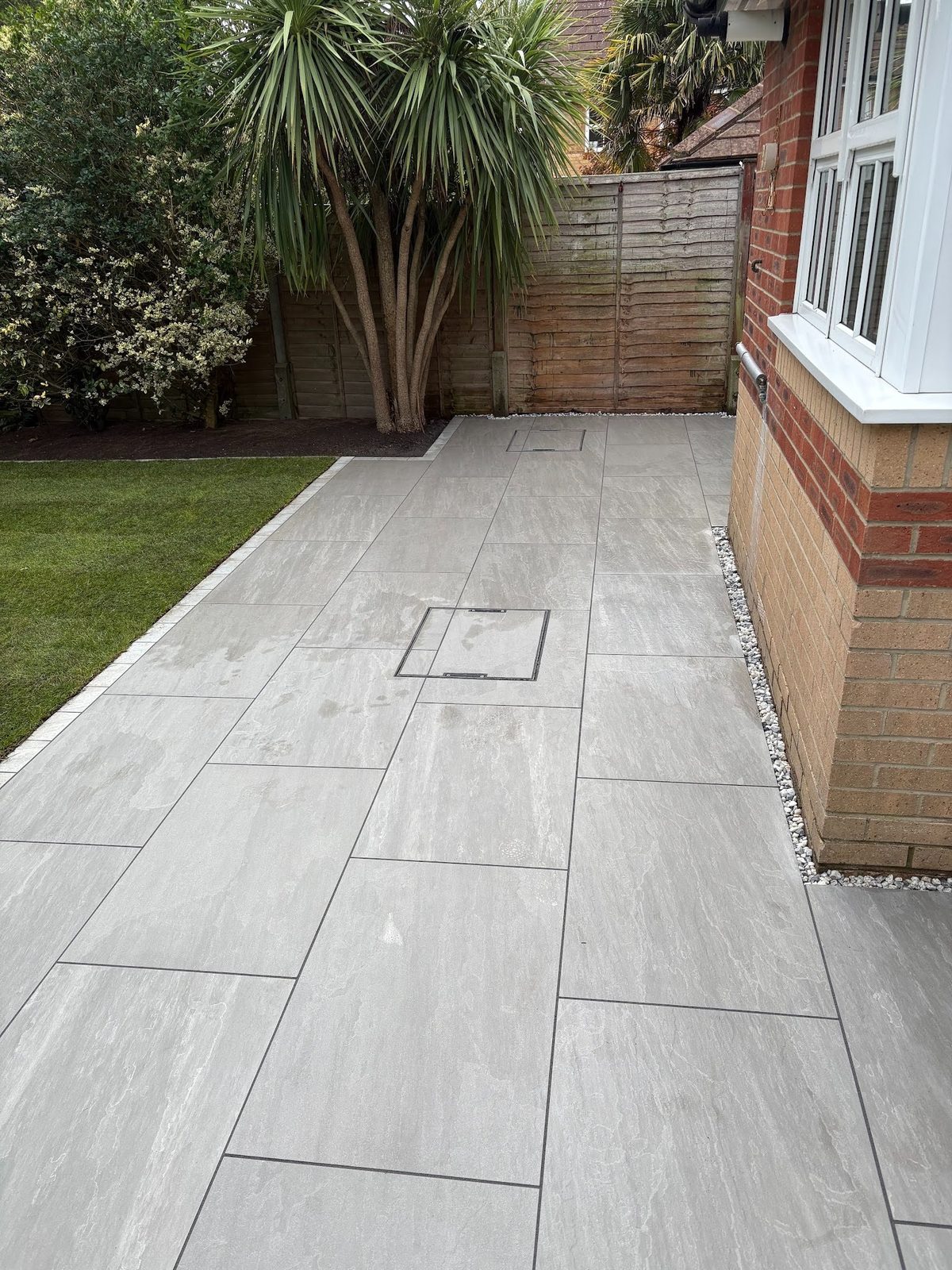 The finished rear patio in Kandla Grey porcelain, laid as one continuous surface and framed by matching porcelain setts.