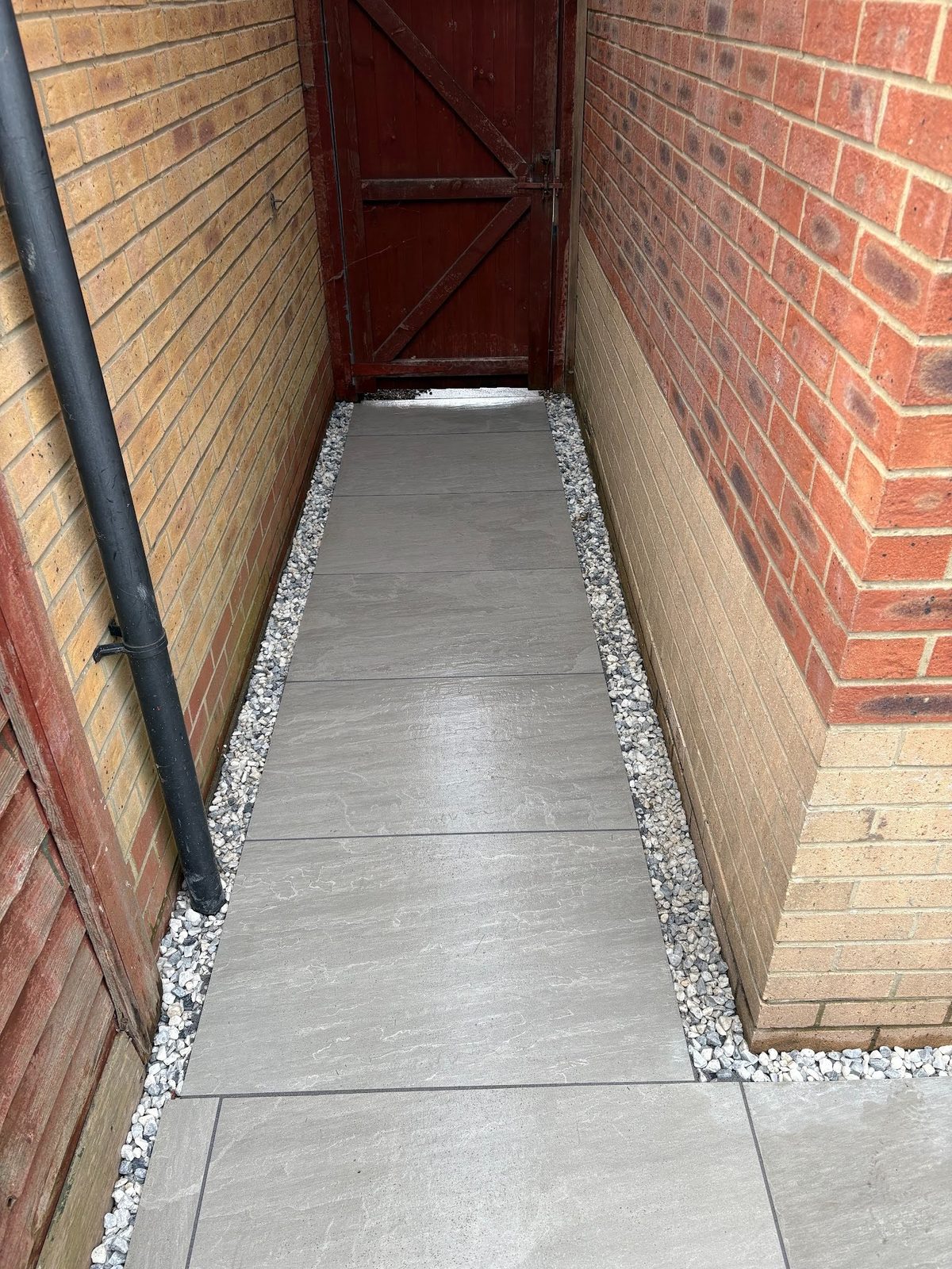The side access path relaid in matching porcelain, edged in gravel for drainage.