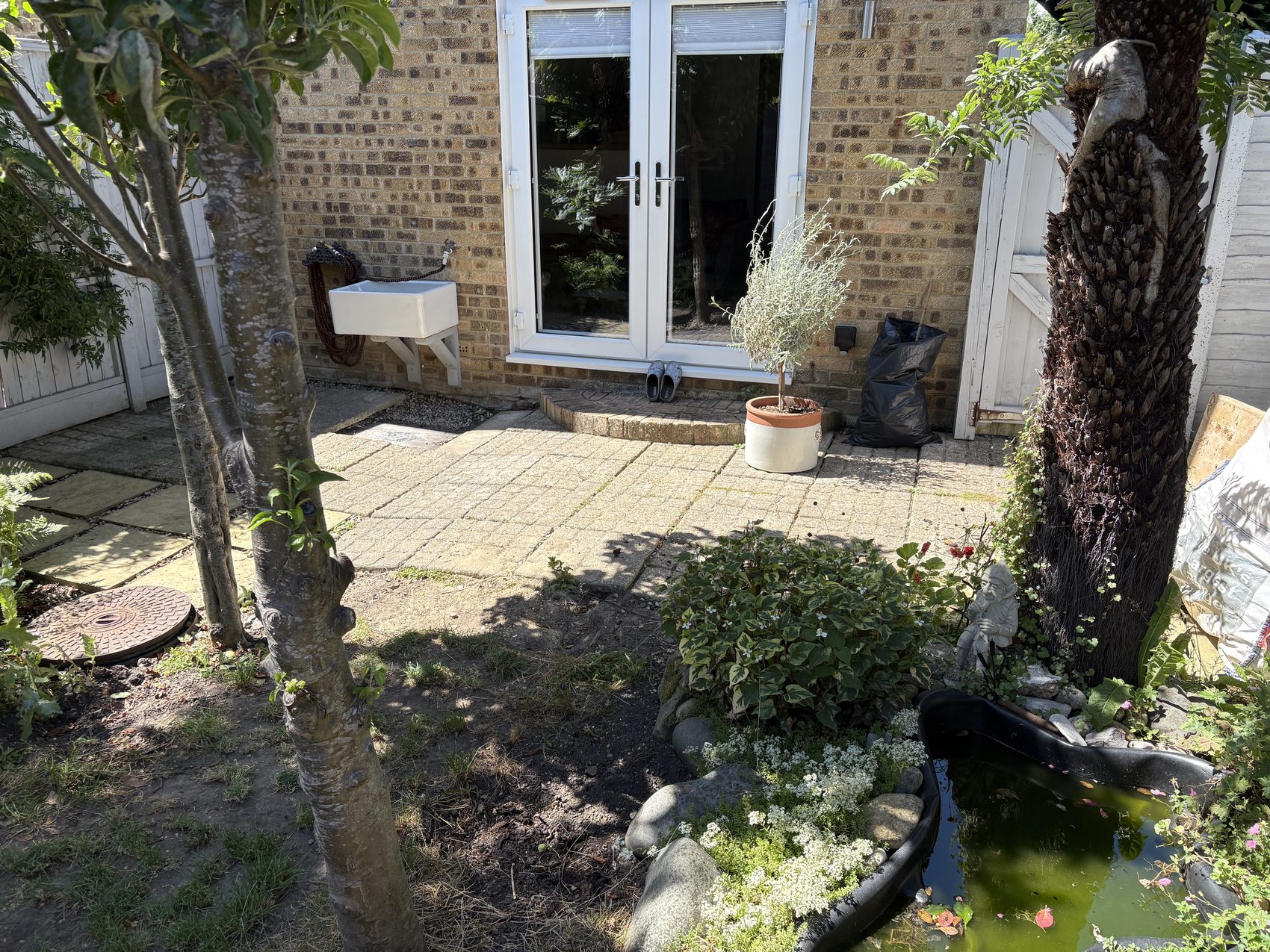 Before: the old utility patio by the back door, with bags of aggregate and an old Belfast sink.