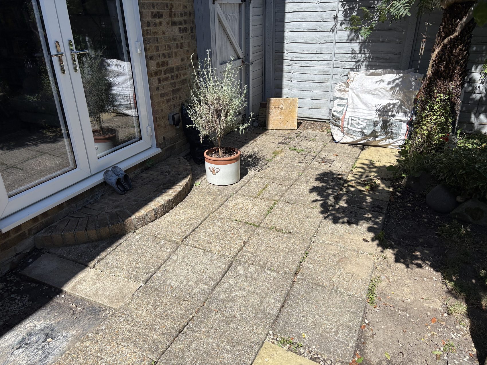 The finished Locks Heath garden: a new buff porcelain patio with brick-faced step, wicker seating, and mature planting either side