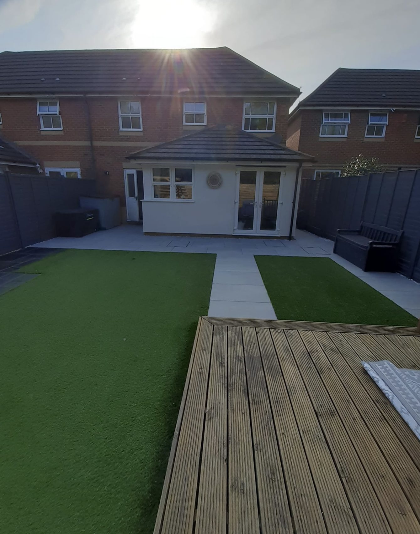 The finished Segensworth garden: dual artificial lawns framed by a Kandla Grey porcelain path running the full width of the plot, timber decking in the foreground.