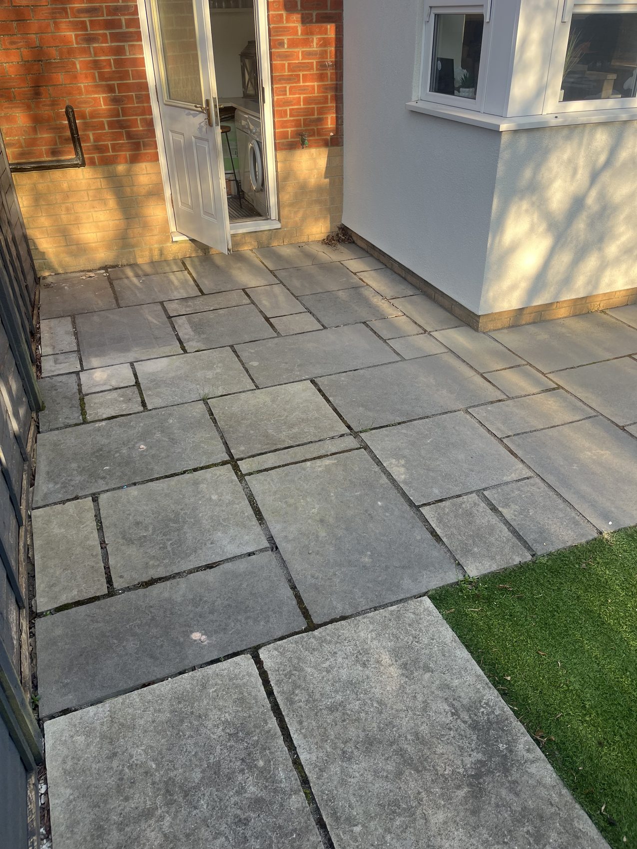 Detail of the Kandla Grey porcelain patio meeting the framed artificial lawn, laid to a clean, true line.