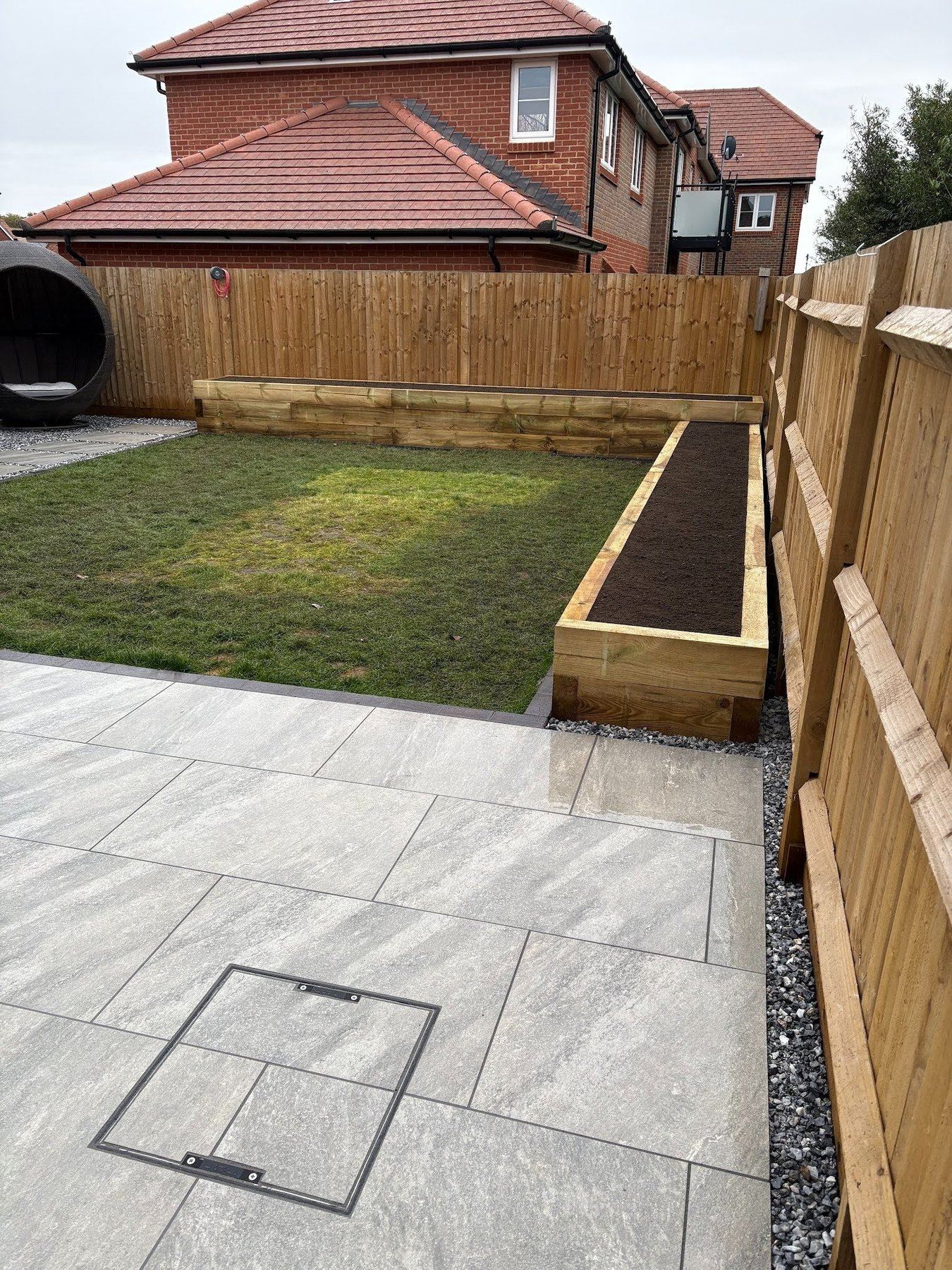 View back from the rear terrace toward the house, showing the path running between the lawn and sleeper bed.