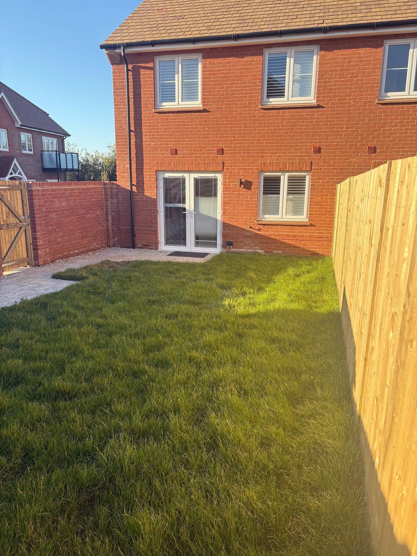 Pre-build view &mdash; the rear of the plot with developer-grade turf and the original concrete patio.