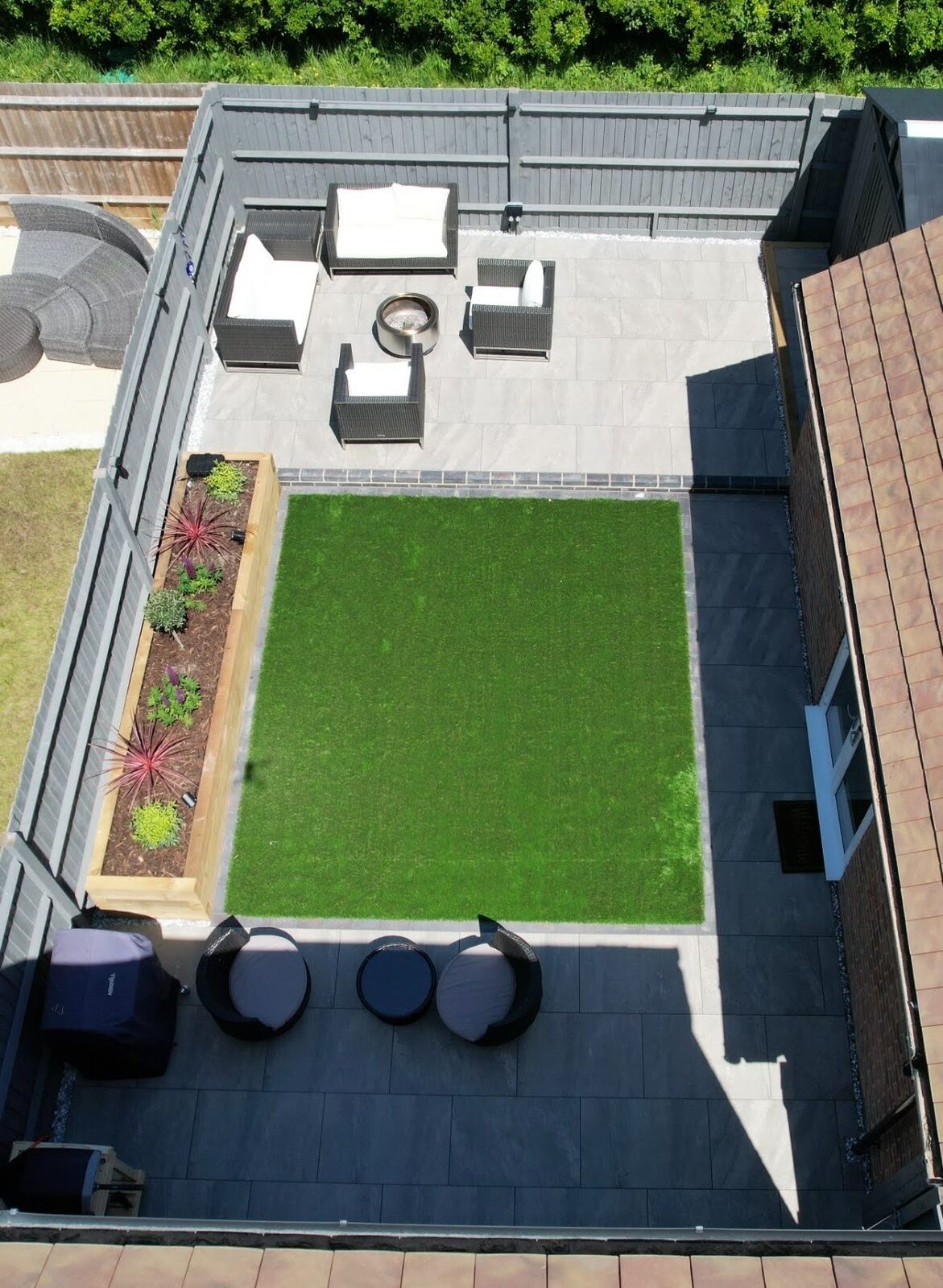 Overhead view of the finished rear garden showing the porcelain surface wrapping the central lawn panel.