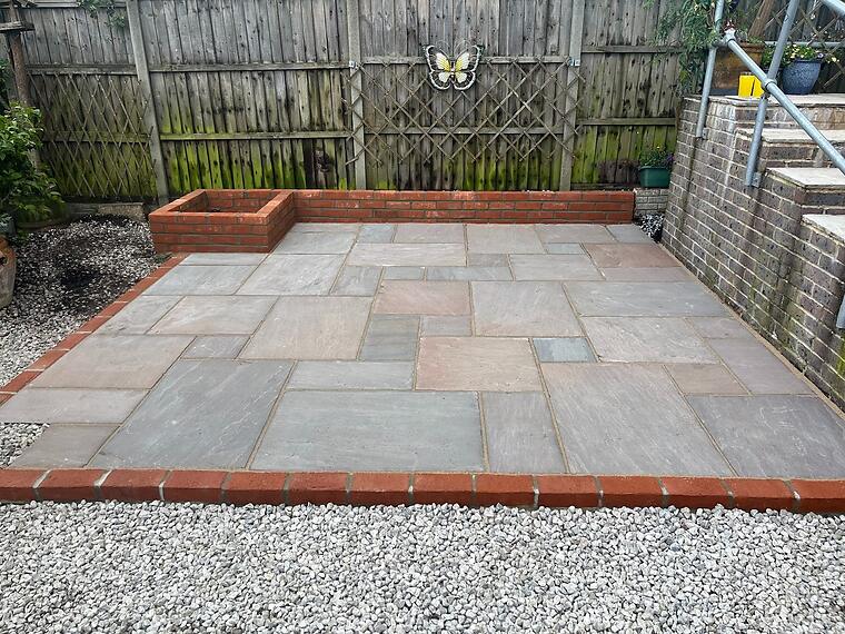 Bottom-of-garden patio, Fareham -- Bottom-of-garden sandstone patio, mixed-size Raj slabs in a random course, Ibstock red multi brick edging and a low retaining wall.