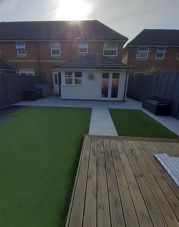 Garden refresh, Segensworth -- Dual artificial lawns framed by a porcelain path running the full width of the plot, timber decking in the foreground.