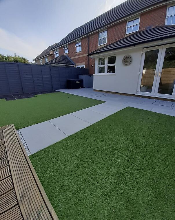 Garden refresh, Segensworth -- A new Kandla Grey porcelain patio and path framed by artificial lawn on both sides, with timber decking to the rear.