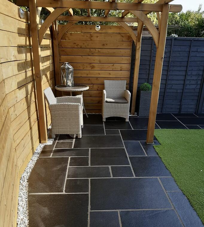 Garden refresh, Segensworth -- The existing black limestone paving, deep-cleaned and relaid true, now anchoring a seating area under the garden's pergola.