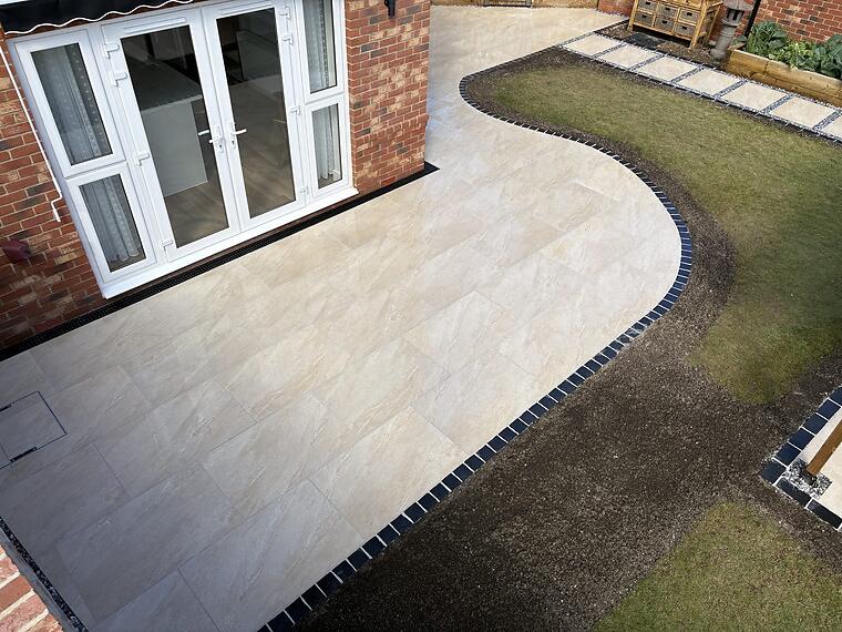 Curved patio, Warsash -- The curved terrace flowing from the back doors into the lawn, framed in black limestone.
