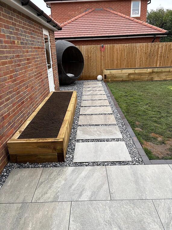 Garden composition, Warsash -- A stepping path of sandstone in granite chippings, with charcoal block edging and a sleeper bed running off the corner.